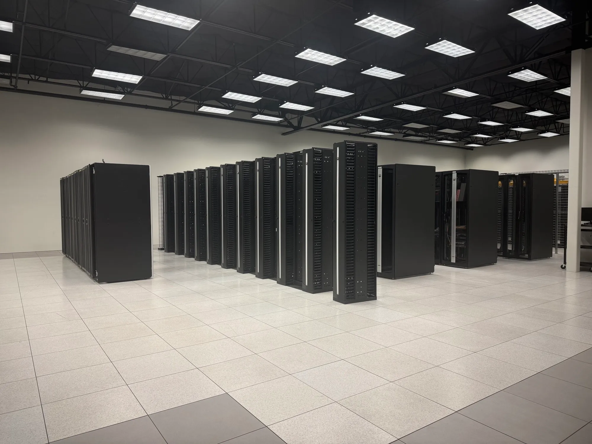 Rows of server cabinets beneath bright ceiling lights in the McKinney data center